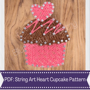 Può includere: Motivo cupcake in string art con un cuore rosa. Il cupcake è marrone e rosa, con capocchie argentate. Il testo "PDF: String Art Heart Cupcake Pattern" è in basso nell'immagine.