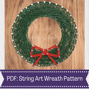 Könnte beinhalten: Grüner String-Art-Kranz mit einer roten Schleife auf einem Holzgrund. PDF: String Art Kranz Muster.