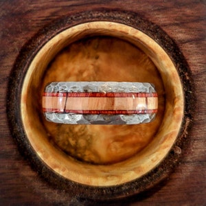 May include: A silver and wood ring with a hammered finish and a thin band of wood.