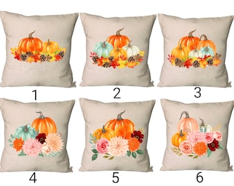 Puede incluir: Seis diseños diferentes de almohadas con un grupo de calabazas con follaje de otoño, flores y piñas. Las calabazas son naranja, blancas y verdes. El follaje es rojo, naranja y amarillo. Las flores son rosas, naranjas y rojas. Las piñas son marrones.
