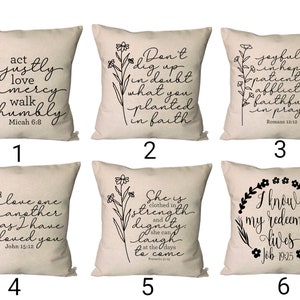 May include: Six beige throw pillows with black floral designs and inspirational quotes. The quotes are: "Act justly, love mercy, walk humbly, Micah 6:8", "Don't dig up in doubt what you planted in faith", "Joyful in hope, patient in affliction, faithful in prayer, Romans 12:12", "Love one another as I have loved you, John 15:12", "She is clothed in strength and dignity, she can laugh, at the days to come, Proverbs 31:25", "I know my redeemer lives, Job 19:25".