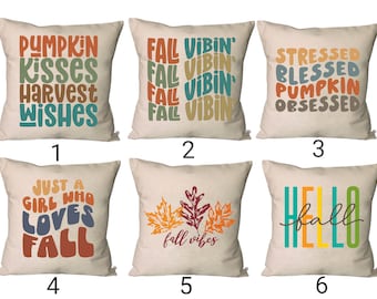 Puede incluir: Seis diseños diferentes de almohadas con texto y gráficos de temática otoñal. Las almohadas son todas de color beige con texto y gráficos coloridos. Los diseños incluyen "Pumpkin Kisses Harvest Wishes", "Fall Vibin'" repetido cuatro veces, "Stressed Blessed Pumpkin Obsessed", "Just a Girl Who Loves Fall", "Fall Vibes" con dos hojas de otoño, y "Hello Fall" con la palabra "Hello" en amarillo, naranja y verde.