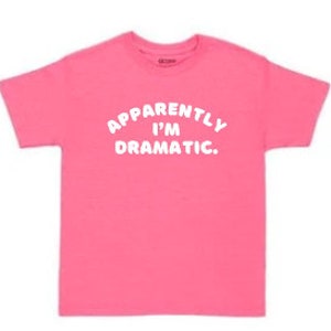 Könnte beinhalten: Pinkes T-Shirt mit weißem Text, der "Anscheinend bin ich dramatisch." lautet.