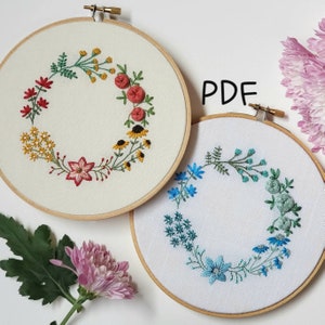 Puede incluir: Dos aros de bordado con diseños florales. El aro de la izquierda tiene una corona de flores amarillas, rojas y verdes. El aro de la derecha tiene una corona de flores azules y verdes. El texto "PDF" está escrito en negro sobre un fondo blanco.
