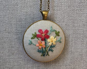 Embroidery necklace with flower bouquet stitched on linen and set in a rustic metal setting.  Fiber art pendant. Hand embroidered.