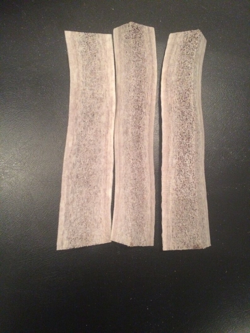May include: Three white deer antler chews, each about 6 inches long, with a slightly curved shape and a rough, textured surface.