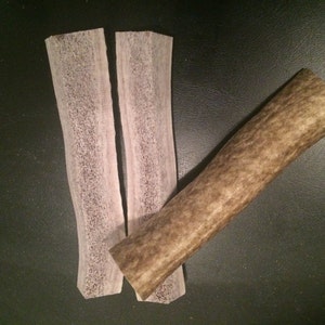 May include: Two thin, flat pieces of light brown antler with a thicker, round piece of antler.