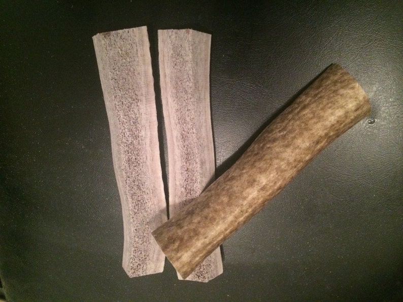 May include: Two thin, flat pieces of light brown antler with a thicker, round piece of antler.