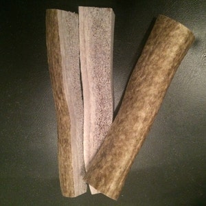 May include: Three antler dog chews, two are light brown with a white center and one is dark brown with a light brown center.
