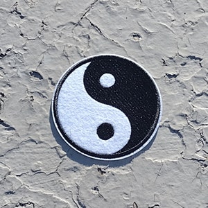 May include: Round Yin and Yang patch with a white and black design. The patch features a white, curved shape on the left and a black, curved shape on the right, with a white dot in the black area and a black dot in the white area.
