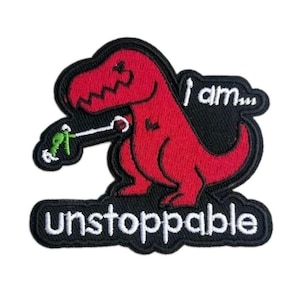 May include: An embroidered patch featuring a red Tyrannosaurus rex holding a small green object with a white string. The text reads I am... and unstoppable in white embroidery against a black background with a thick black border.