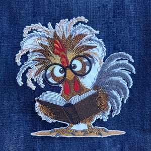 May include: Embroidered patch featuring a cartoon rooster wearing glasses and reading a book. The rooster has brown, white, and red feathers, with a gray tail. The patch is on a blue denim background.