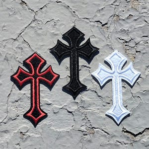 May include: Three iron-on patches in the shape of a cross. The crosses are black, red, and white.