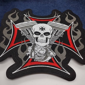 May include: Black and red embroidered patch with a skull and crossbones design. The skull is surrounded by a motorcycle engine and flames.