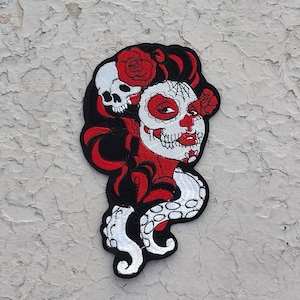 May include: Embroidered patch featuring a red and white sugar skull with black hair and a red rose. The skull is surrounded by a black and white octopus.