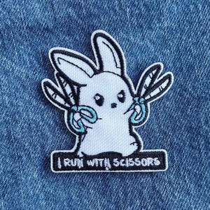 May include: White embroidered patch of a bunny holding two pairs of scissors with the text "I run with scissors" below.