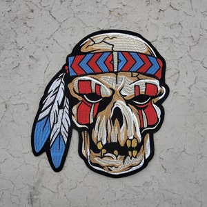 May include: A colorful embroidered patch of a skull wearing a red, white, and blue headband with a feather on the side. The skull has a tribal design on its face.