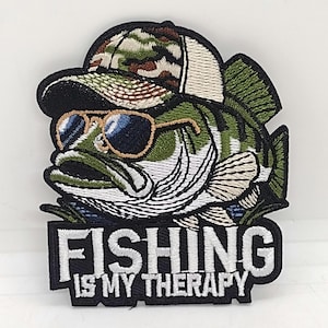 May include: Embroidered patch featuring a cartoon bass wearing sunglasses and a camouflage hat. The fish is green, white, and black. The patch has the text "FISHING IS MY THERAPY" in white letters on a black rectangle.