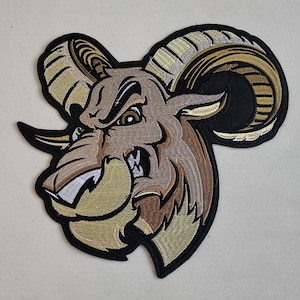 May include: Embroidered patch of a brown and gold ram with a fierce expression. The ram's horns are curled and have a striped pattern. The patch is on a black background.