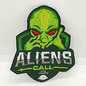 May include: Green alien with red eyes, holding its chin, with the text "ALIENS CALL" in white and gray letters on a green background.