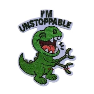 May include: An embroidered patch featuring a green dinosaur with a wide, laughing mouth and mechanical claw arms. Above the dinosaur, the text I'M UNSTOPPABLE is stitched in black thread. The design has a white border and a white background.