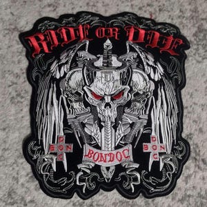 May include: Black and white embroidered patch with a skull and crossbones design. The patch features a sword, wings, and the text "Ride or Die" and "Bondoc".
