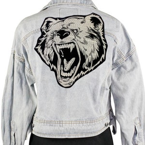 May include: A light blue denim jacket with a black and white embroidered bear patch on the back.