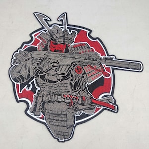 May include: Embroidered patch featuring a samurai warrior in gray armor, holding a rifle. The samurai has a red face mask and accents. The patch is set against a red and black background, with a detailed design and a black border.