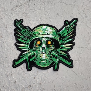 May include: A green and black patch featuring a skull wearing a gas mask and military helmet. The skull has glowing orange eyes. Green rifles and knives form a wing-like design around the skull. The patch has a black border.