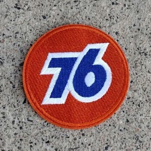 May include: A round, orange patch with the number 76 in white and blue embroidery.