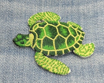 May include: Green embroidered sea turtle patch with yellow accents. The turtle is swimming to the right.
