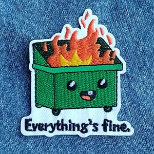 May include: Embroidered patch featuring a green dumpster on fire with a smiling face. The flames are orange and yellow. The text "Everything's fine" is below the dumpster in black letters.