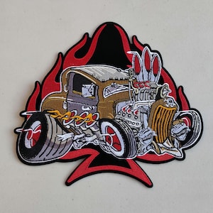 May include: An embroidered patch featuring a cartoon hot rod car with flames and an ace of spades design. The car is brown, gray, and red with a detailed engine and wheels.