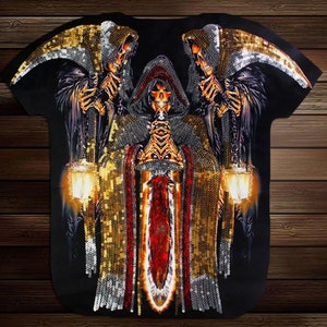May include: Black t-shirt with a graphic print of three skeletons wearing robes and holding swords and lanterns. The skeletons are covered in gold and silver sequins.