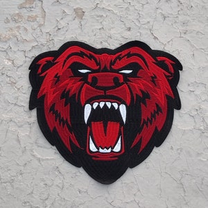 May include: Red embroidered patch of a bear with a black outline and a large open mouth showing sharp teeth.