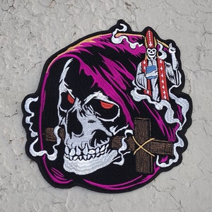 May include: Embroidered patch featuring a skull wearing a purple hooded robe, holding a cross in its mouth, with a skeleton wearing a bishop's robe and mitre floating above it.