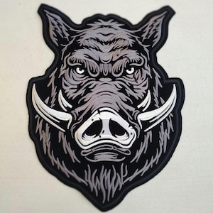 May include: Black and white embroidered patch of a wild boar's head with large tusks.