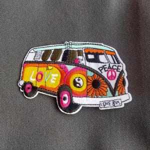 May include: A colorful patch featuring a retro van with the words "LOVE" and "PEACE". The van is decorated with a sunflower, yin-yang symbol, and a peace sign. The patch has a white border and is set against a gray background.