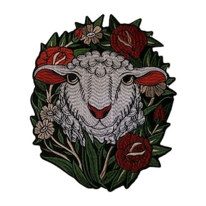 May include: An embroidered patch featuring a white sheep head surrounded by dark green leaves, red roses, and small beige flowers. The sheep has detailed grey stitching for its wool, dark eyes, and a red nose, set against a plain white background.