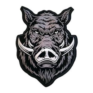 May include: A black and grey embroidered patch featuring the head of a wild boar. The design displays a detailed illustration of the animal with prominent white tusks, a dark snout, and textured fur patterns, all outlined with a thick black border.