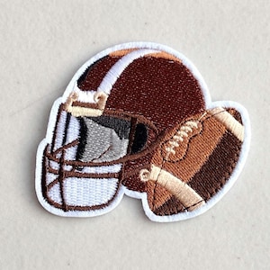 May include: Embroidered patch featuring a brown football helmet and a brown football. The helmet has a white face mask and the football has white laces.