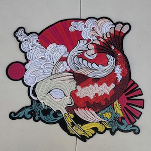 May include: Embroidered patch featuring a koi fish design with red, white, and yellow accents. The fish is set against a red fan and stylized waves. The patch has a black border.