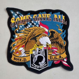 May include: Embroidered patch with an American flag, eagle, and the words "Some Gave All" and "Born in the U.S.A."  The patch also features a POW/MIA emblem with the text "You Are Not Forgotten."