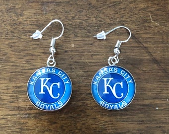 May include: A pair of silver dangle earrings with blue and white Kansas City Royals logo charms.