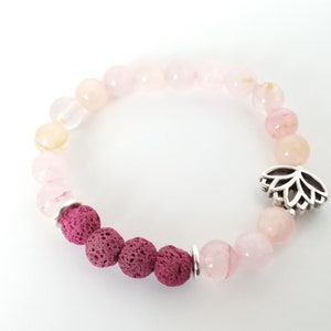 May include: A pink and white gemstone bracelet with a silver lotus charm and dark red lava rock beads.
