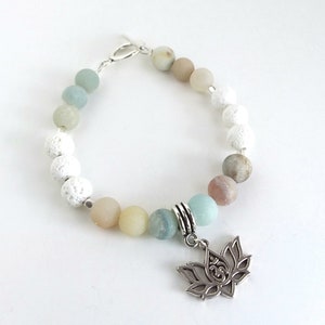 May include: A white and green beaded bracelet with a silver lotus charm. The bracelet features white lava beads, green and white agate beads, and a silver clasp.