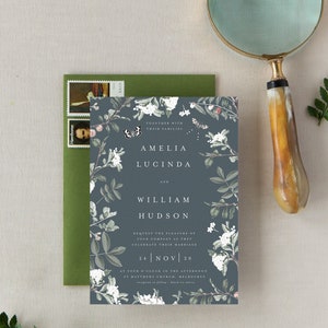 May include: A blue wedding invitation with a floral design featuring white flowers, green leaves, and butterflies. The text reads "Amelia Lucinda and William Hudson, Request the pleasure of your company as they celebrate their marriage, 24 Nov 20, at four o'clock in the afternoon, St. Matthews Church, Melbourne."