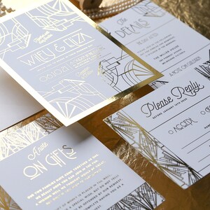 May include: A set of wedding stationery with a gold and pale grey Art Deco theme. The suite includes an invitation, details card, reply card, and gift information card. The invitation features the names "Wiley & Eliza" and the date "06.10.21".