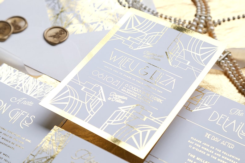 May include: A stylish wedding invitation set with gold foil accents on a pale grey background. The invitation displays the names "Wiley & Eliza" and event details. Includes matching envelopes and wax seals.