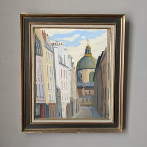 以下が含まれることがあります： ヨーロッパの街並みを描いた油絵。建物と遠くにはドーム型の構造物があります。このアートワークは、金と黒のフレームに収められています。絵画には「N 76」と署名されています。